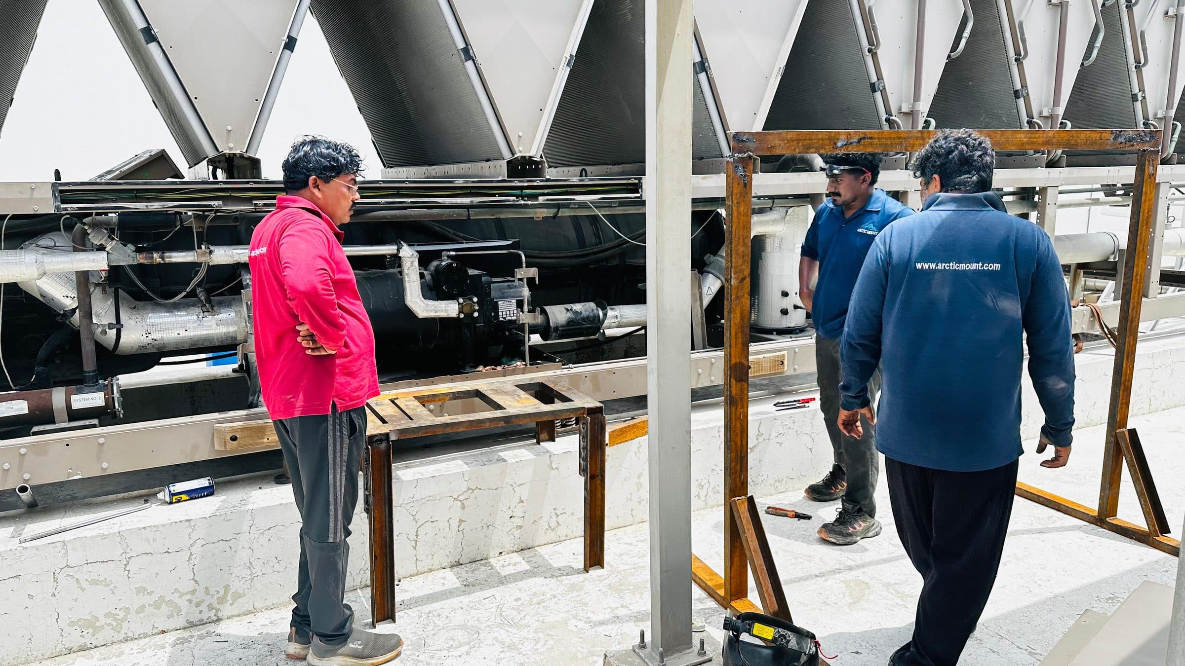 Technicians setting up a steel frame beneath the chiller for compressor removal