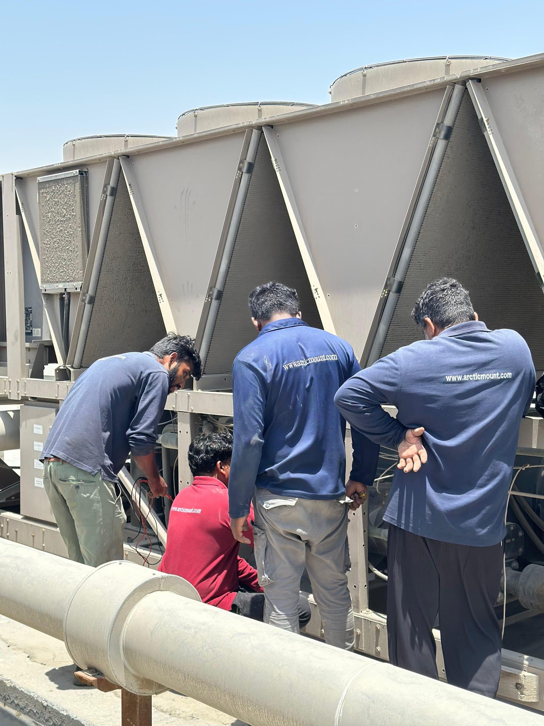 Four Arctic Mount technicians at a rooftop chiller